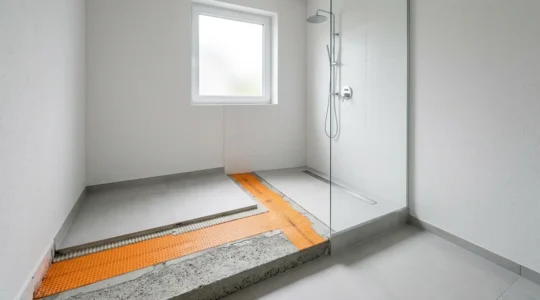 Vue détaillée d'une douche à l'italienne moderne avec système d'étanchéité visible sous carrelage, caniveau et pente optimale
